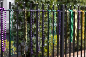 Colorful beads in purple, green, and yellow are hanging on a black iron fence.