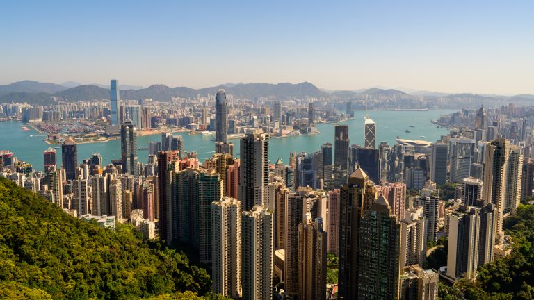 A view of Hong Kong harbour taken on a sunny day.  The view is north facing into Kowloon with the main harbour area visible, including skyscrapers like the ICC and IFC