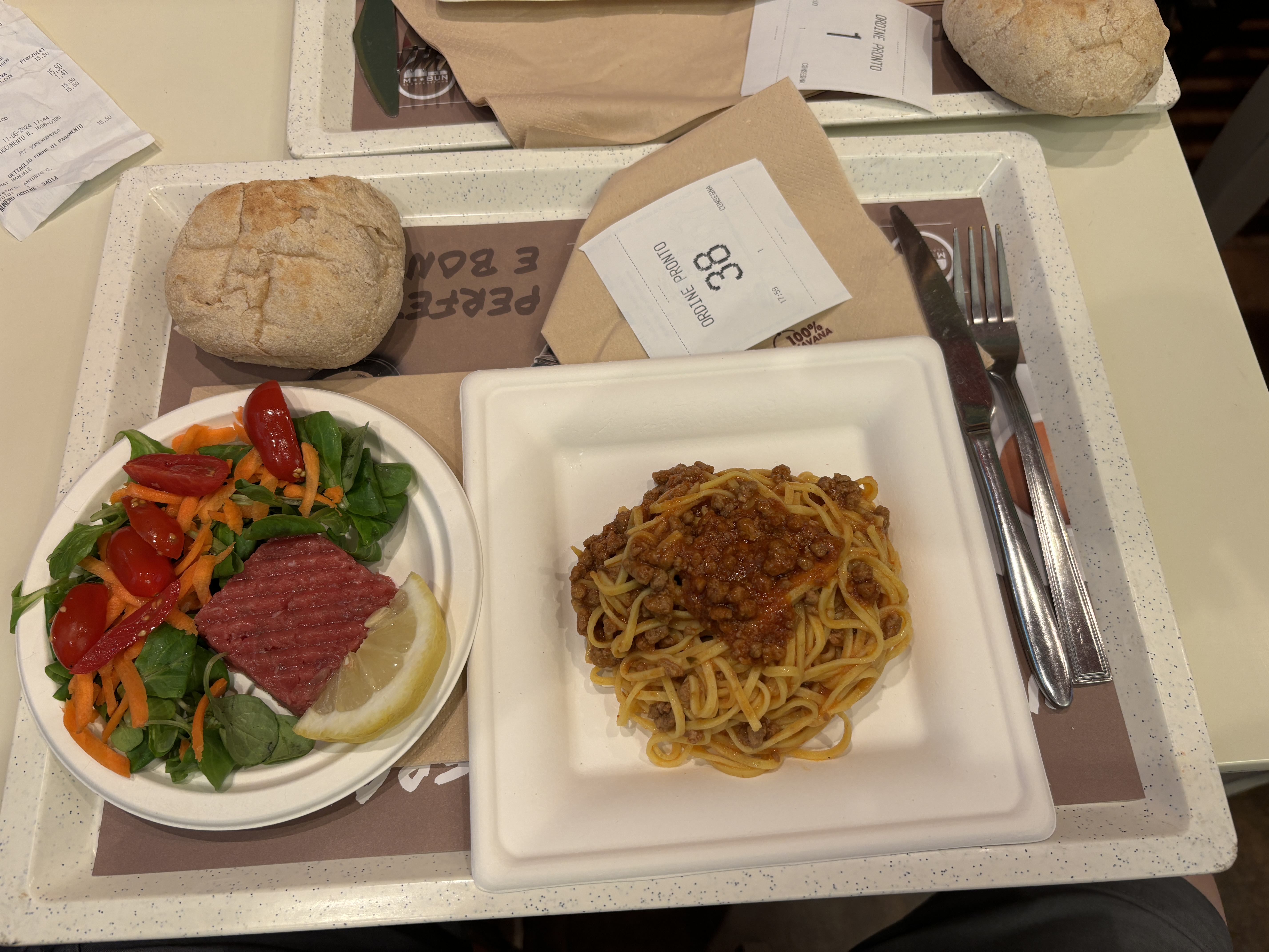 Food from an Italian "fast food" restaurant. Pasta with marinara, steak tartar with fresh vegetables.