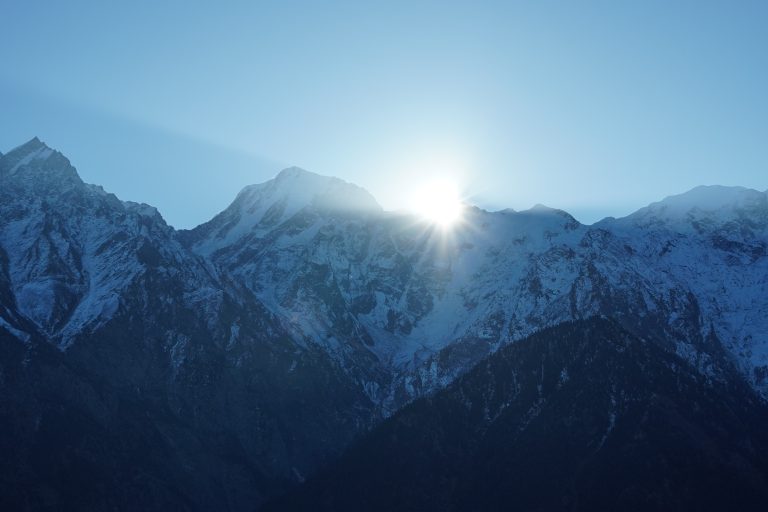 Incredible view of a sunrise in the Himalayas. The sunlight creates a star-like pattern as it peeks above the mountain tops. The photo was taken at Manali, Northern India.