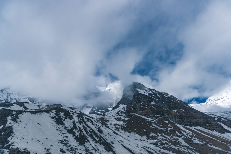 Snow-capped mountains partially obscured by clouds in the morning during Annapurna Base Camp trek, Nepal.