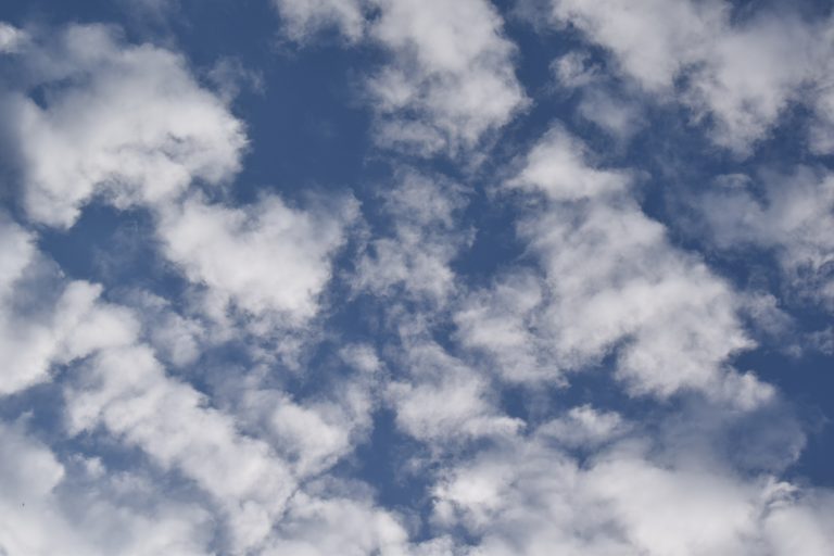 A bright blue sky filled with scattered, fluffy white clouds.