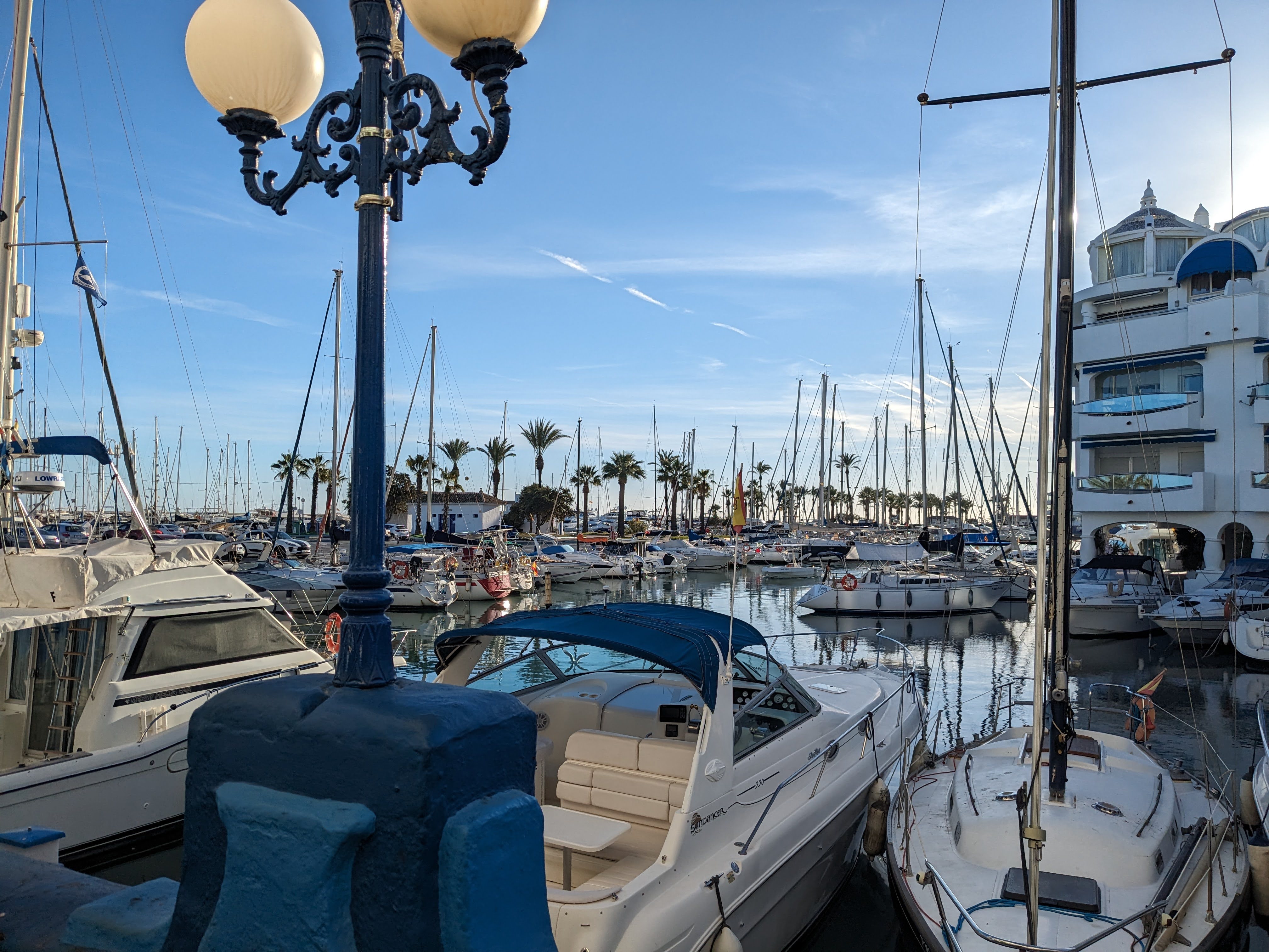 Boats in the water with a building and lightpost in Puerto Marina Benalmadena