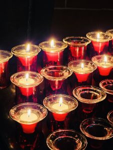 Rows of glowing white candles in red glass