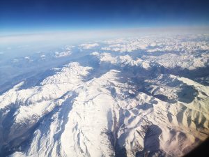  Aerial view of the Pyrenees mountain range with snow-covered peaks under a clear blue sky.