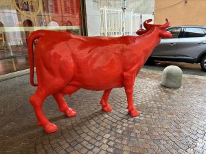 A red statue of a cow on the streets of Torino, Italy.