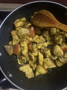 View larger photo: Cooked pieces of pork meat in a black frying pan with a wooden spatula.