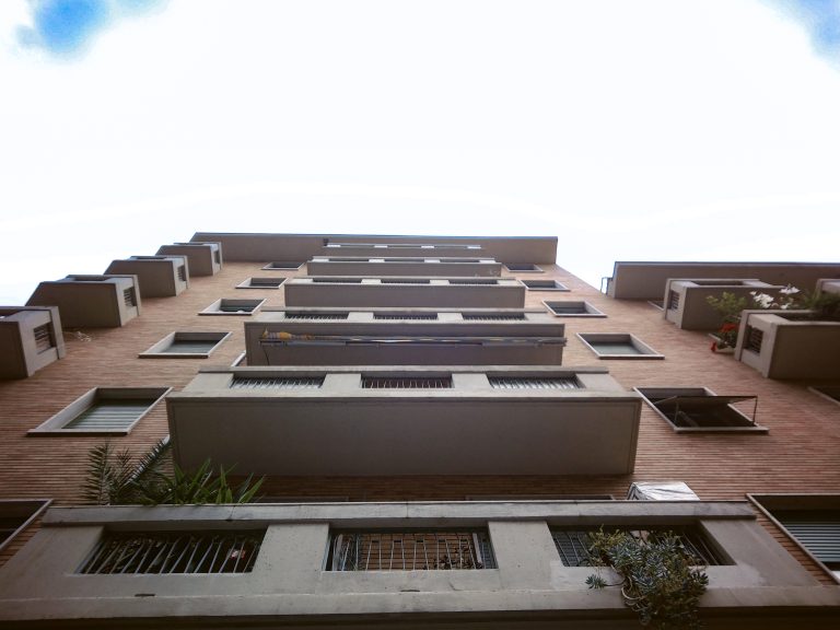 Looking up, a building with multiple balconies and a blue sky.