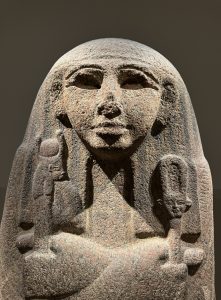 A stone Egyptian statue from the chest up.