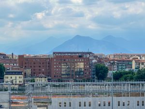 View larger photo: New buildings being constructed in front of older ones in Torino, Italy. Mountains in the distance appear different shades of blue.