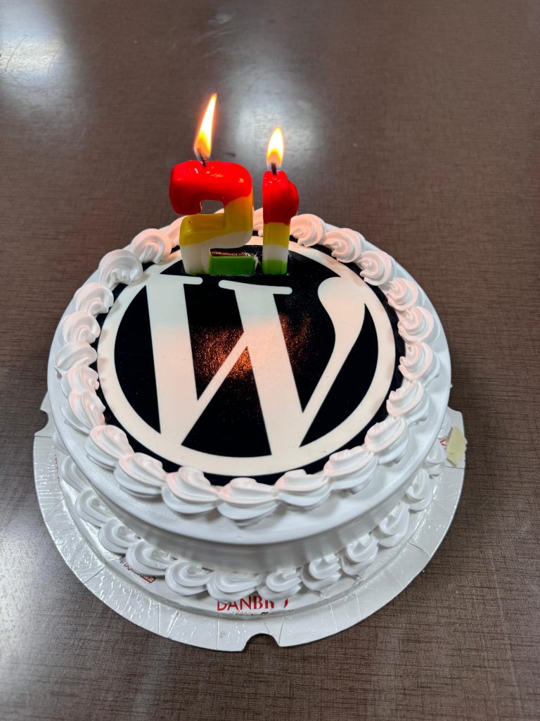 A cake with the WordPress logo and candles that are the number 21