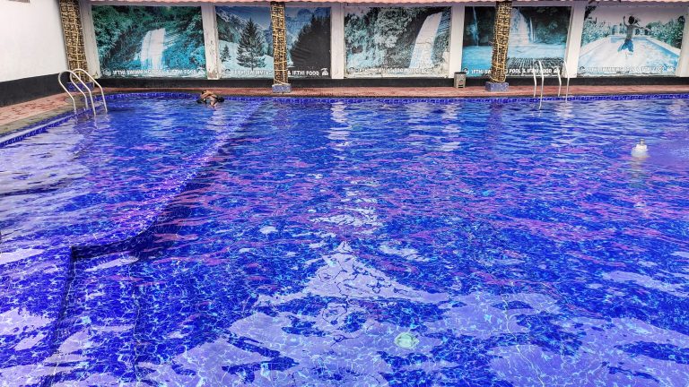 A large, clear blue swimming pool with tile steps.