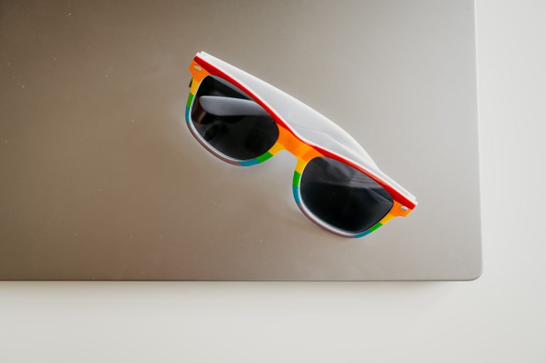 Pride themed rainbow sunglasses on a grey laptop with a grey background.