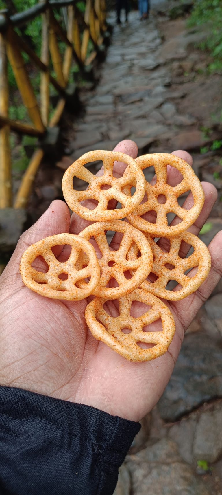 A hand holding some of the ring-like chips, red pepper on it