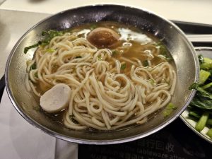 View larger photo: A steaming bowl of Taiwanese noodle soup with a halved tea egg and fish ball.