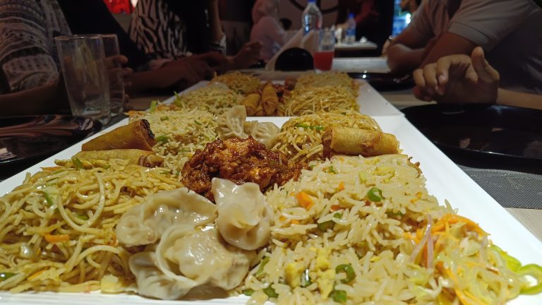 Different types of Ramzan special dishes on plates on a table. The hands of the diners can be seen at the table.