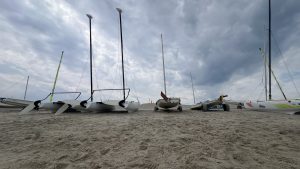 Several catamarans and sailboats sitting on the bayside beach with sand in the foreground and whispy clouds in the background (Lewes Public Beach, Delaware)