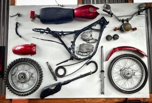 Display of motorcycle accessories and spare parts arranged hanging on a wooden wall.