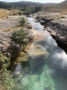 View larger photo: A scenic hill stands in the background, with a clear fountain flowing over stones. The clean water reflects the natural beauty, creating a peaceful and beautiful view.