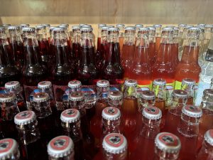 Rows of multicolored glass drink bottles with metal tops.