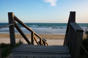 Wooden stairs leading to a empty beach on a sunny day