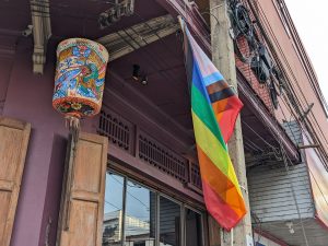 Progress Pride Flag standing still on an electric pole. 