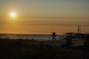 Sunset over a empty beach with a clear sky. A watch tower is visible in the middle