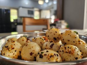 View larger photo: A close-up shot of a bowl of seasoned steamed rice balls. Which are covered in spices and herbs.