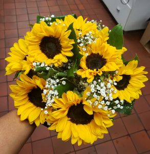 View larger photo: Close up of the top of a hand tied circular style bridal bouquet with sunflowers and baby's breath.