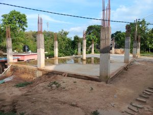 Rising from the ground, a skeleton of steel and concrete awaits its future. Puddles reflect the promise of progress on this new development.