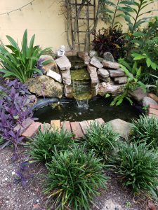 View larger photo: Stone Garden waterfall fountain surrounded by green and flowering plants