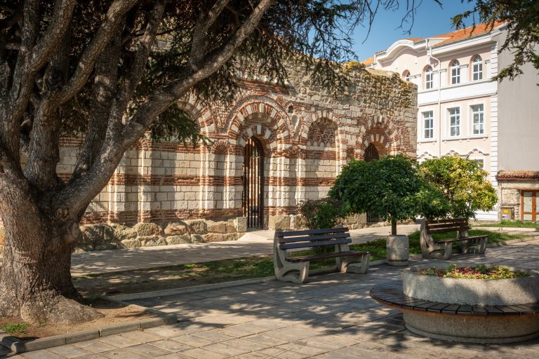 The Church of St John Aliturgetos in Nessebar, Bulgaria. A tree and benches can be seen in front of the remains of the 14th century church.