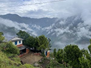 Village house with monsoon clouds scattered on the hills in the distance.