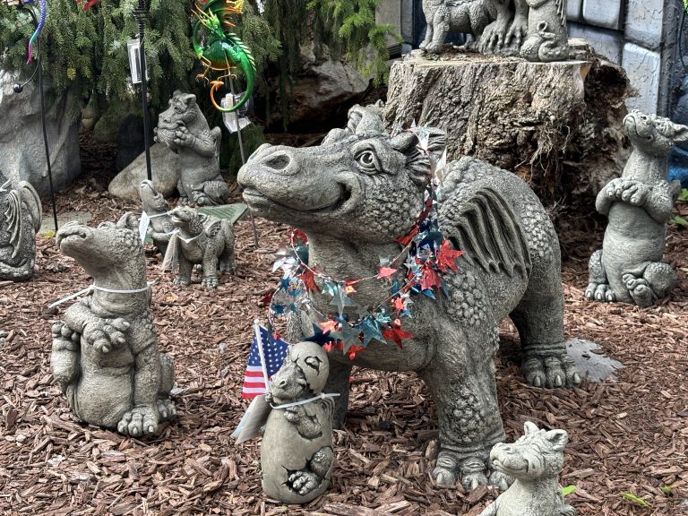 Red, White, and Blue garland decorating concrete dragons, with one holding a flag of the USA.