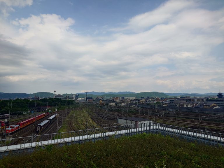 Railway yard view towards Kyoto’s main railway station, mountains and blue sky in the background.