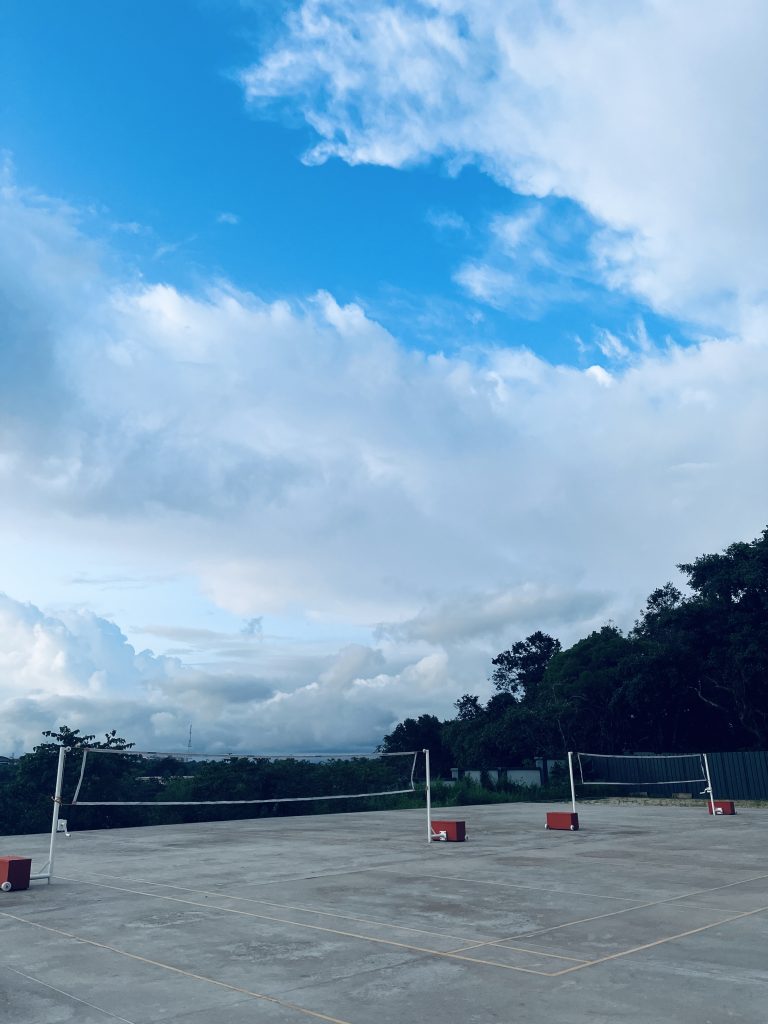 Badminton courts with a bright blue sky with wispy clouds.