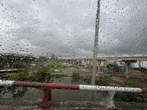 View of a rainy cityscape through a window with water droplets.