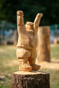 View larger photo: A crude wooden figurine carved from a small log. The figure has its arm raised, and appears to be wearing wooden shoes.