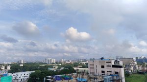 A stunning city skyline view from a rooftop, showcasing tall buildings and a vibrant urban landscape under a lightly clouded sky.