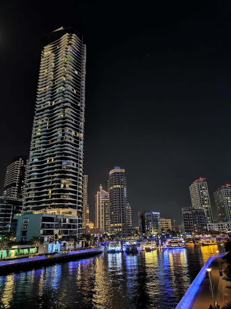 Brightly lit river in downtown Dubai at night with towers on either side.