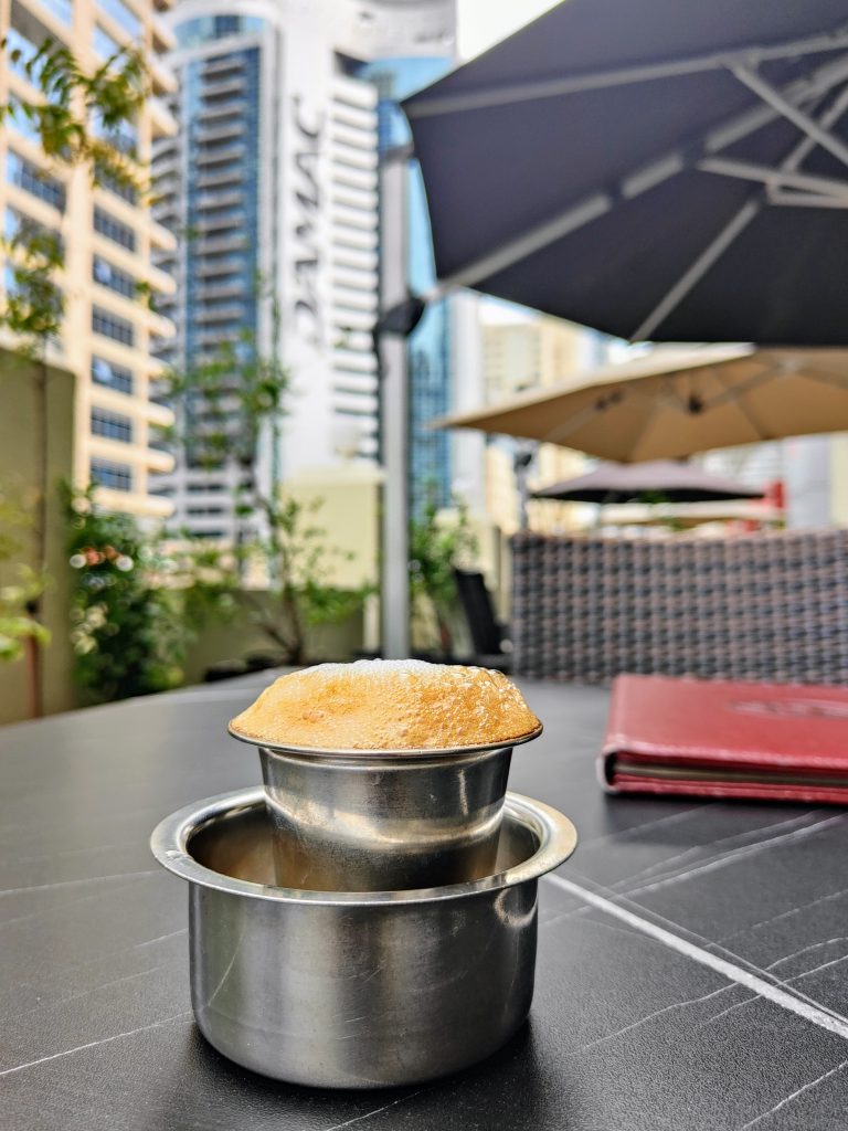 Filter Coffee, served on a terrace at the Dubai Marina. Several buildings can be seen in the background.