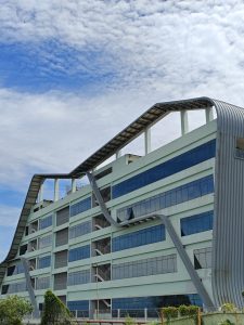 Cyberpark. A multistory building with large, horizontal windows on each floor. The building features unique architectural elements, including upward-curving metal structures that loop over the roof and extend down the sides. 