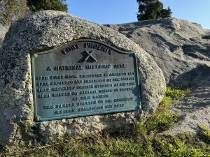 A rock with a commemorative plaque at Fort Phoenix in Fairhaven, Massachusetts. The plaque commemorates the site as a national historic site, and lists several historic dates during American based wars. 
