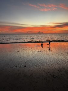 黄昏时分，孩子们在海边的低浪中奔跑。