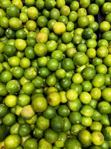 View larger photo: A pile of fresh green Lemons, some with slightly yellowing skin, closely packed together.