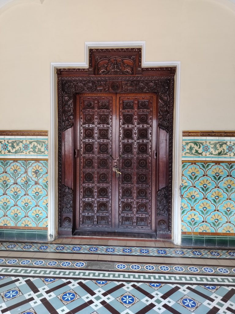 This is an internal door with intricate wood carving. This image was taken in the internal spaces of the Mysore Palace, India.