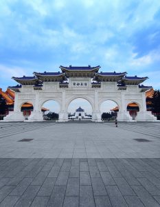 This image shows the grand outer gate of chiang kai-shek memorial in taiwan, featuring traditional chinese architecture with five arches and intricate carvings. The memorial building with its blue roof is visible in the distance, framed by the central arch.