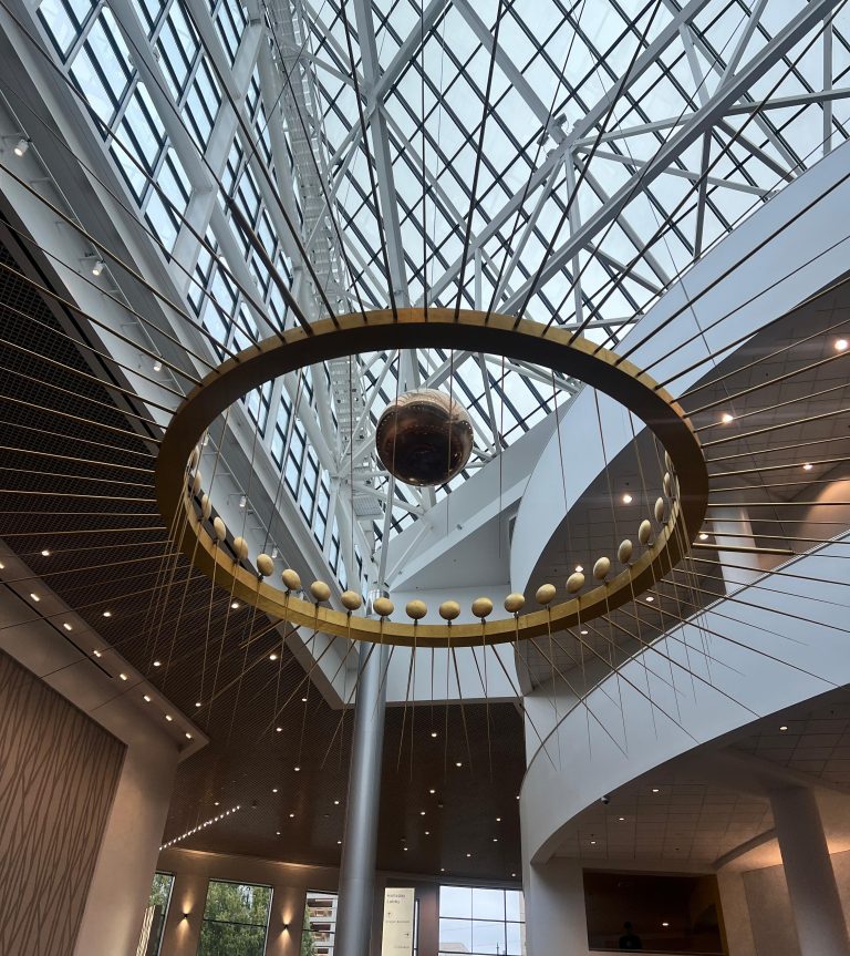 Oregon Convention Center Interior, the ceiling fixture is a kinetic sculpture with a swinging brass pendulum.