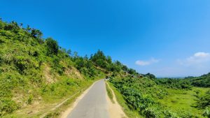 Straight roads in between hill and green fields