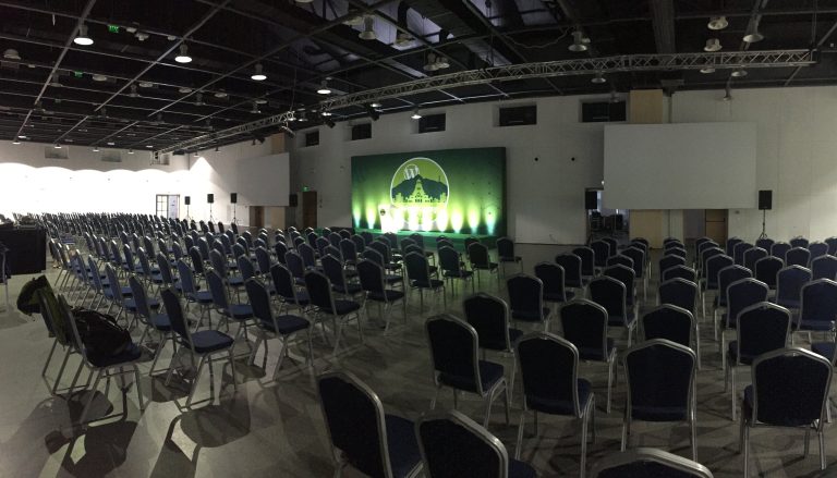 WordCamp Sofia hall set up with a screen lit up with the logo and hundreds of empty chairs.